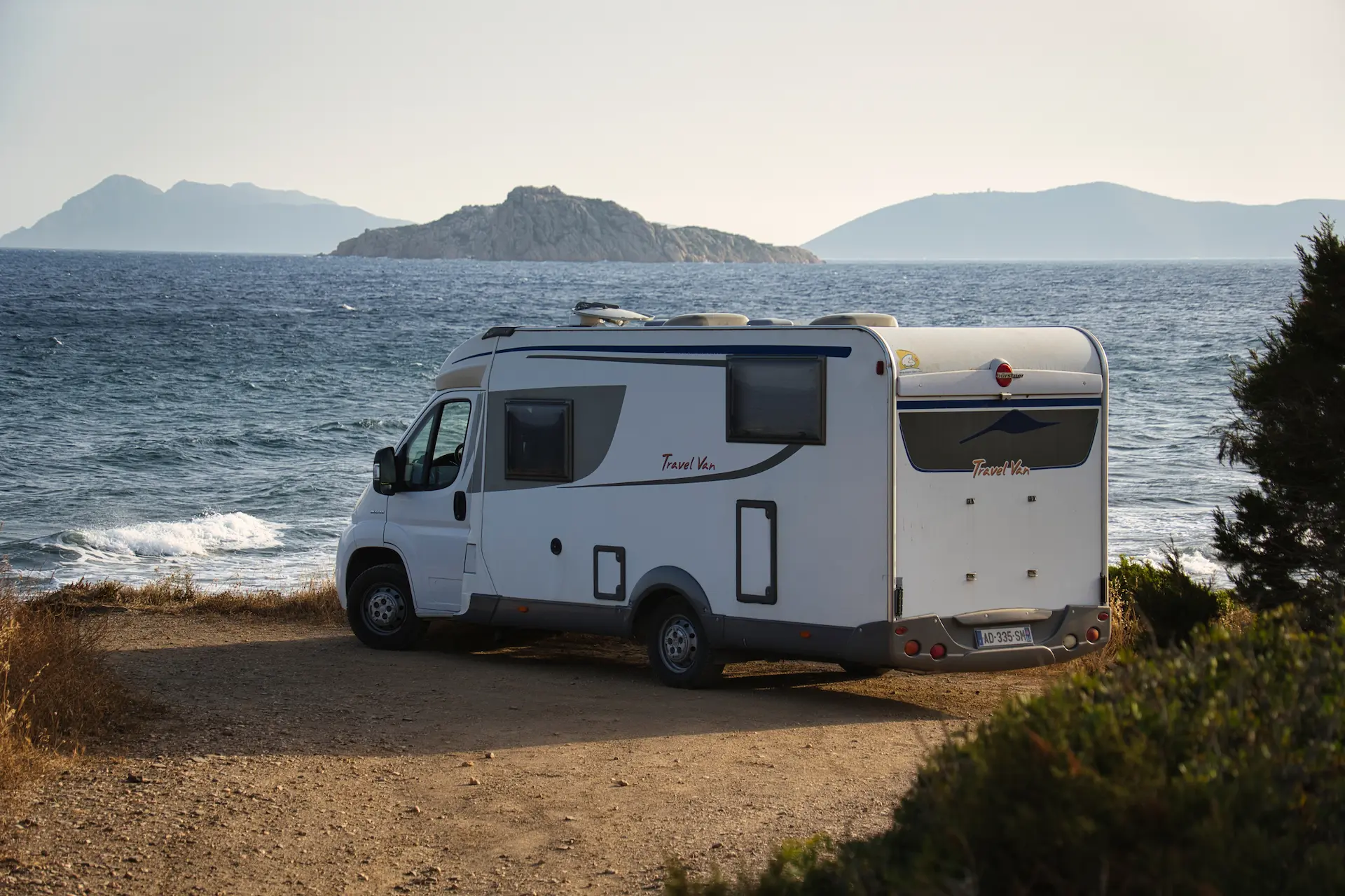 Caravan parked on the beach, with a view of the ocean and some islands in the distance