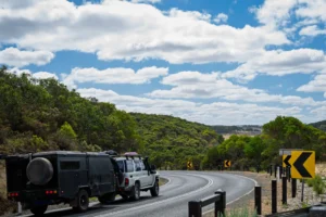 Four wheel drive truck towing a caravan that the driver purchased on a shared caravan loan on the scenic coastal drive, Great Ocean Road, Victoria, Australia